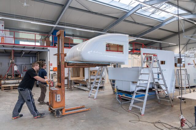 Montage eines Tischer Kabinenmoduls auf Hubvorrichtung – Mitarbeitende mit Leitern im Einsatz.