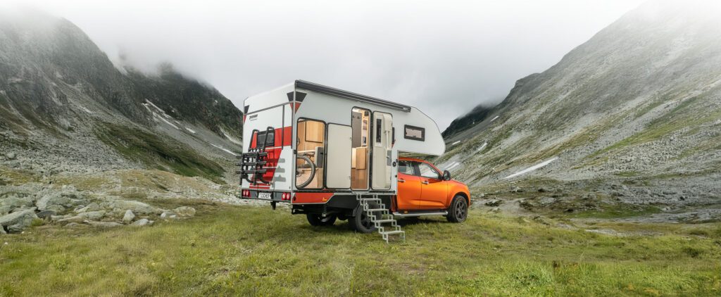 Tischer Trail 260SP Flatbed auf Isuzu D-Max von hinten rechts, Außentreppe und Stauraum sichtbar.