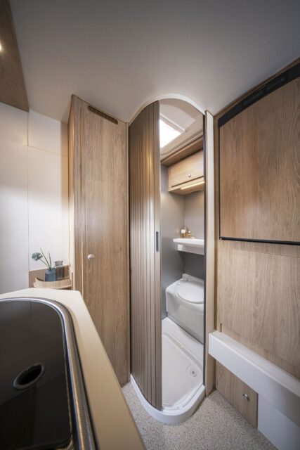 Blick aus der Küche in den Badbereich mit runder Schiebetür und Toilette in Tischer Wohnkabine