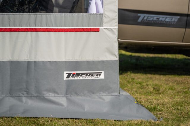 Außenwand des Vorzelts mit Tischer Logo und rotem Zierstreifen – Detailaufnahme.
