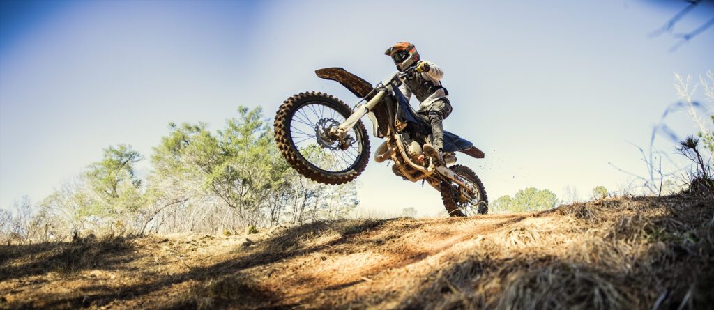 Dirtbiker doing a jump in a wooded area